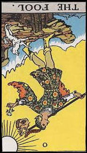 The Fool Tarot Card Reversed from the Major Arcana of the classic Rider Waite Tarot deck. The Fool card reversed depicts the upside down image of a young man walking towards the edge of a cliff, looking to the sky, seemingly unaware of the potential danger that awaits. He carries a bindle with a small sack over one shoulder and a white rose in his other hand, and wears a red feathered cap. He is accompanied by a small white dog. The number zero is at the bottom. The sun, a yellow sky and ice-capped mountains form the backdrop. Explore The Tarot Guide and discover The Fool Tarot card meanings for Love, Relationships, Career, Money, Health, Spirituality, General, Keywords and more!